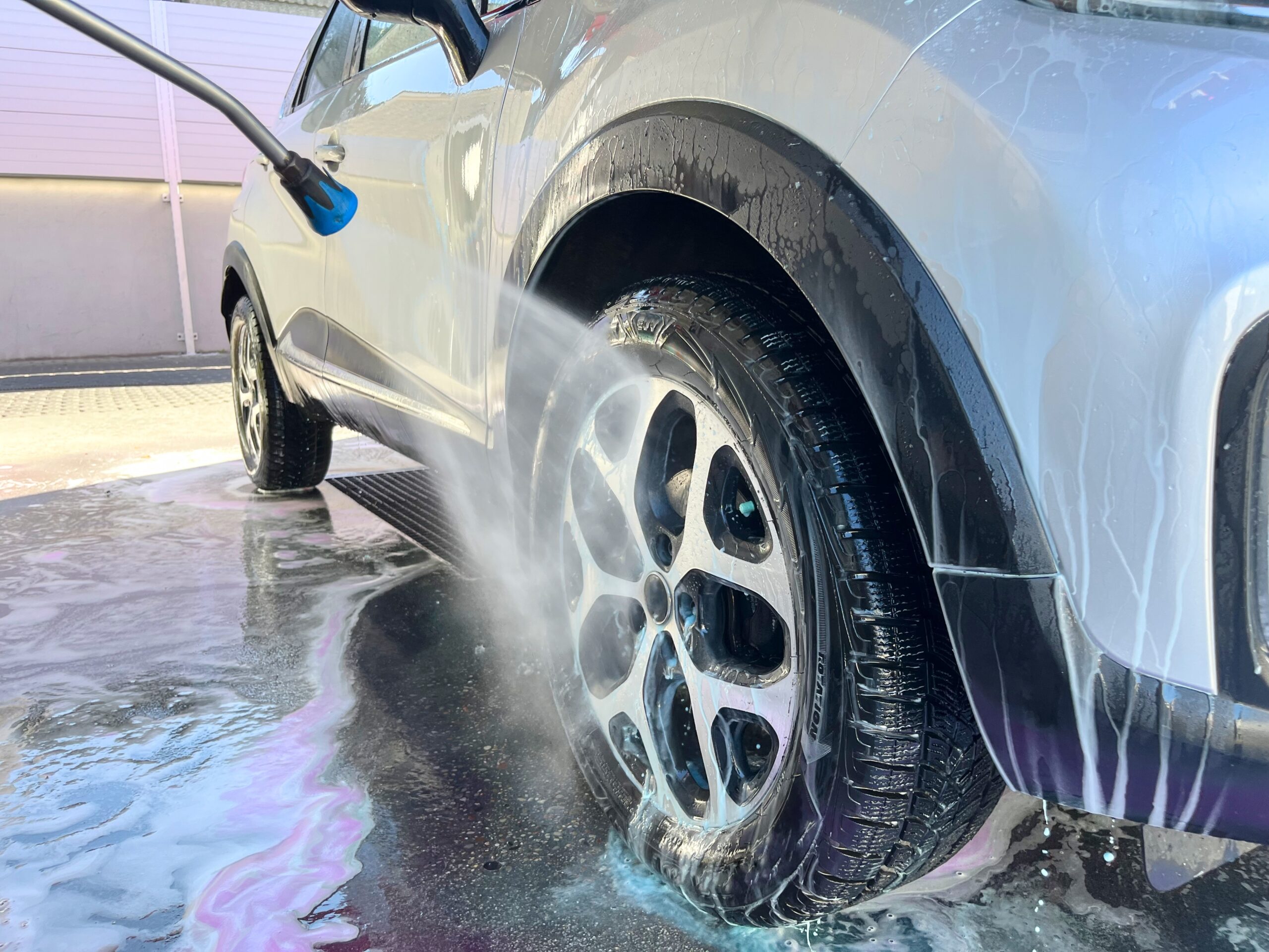 A silver car being rinsed off after a cleaning