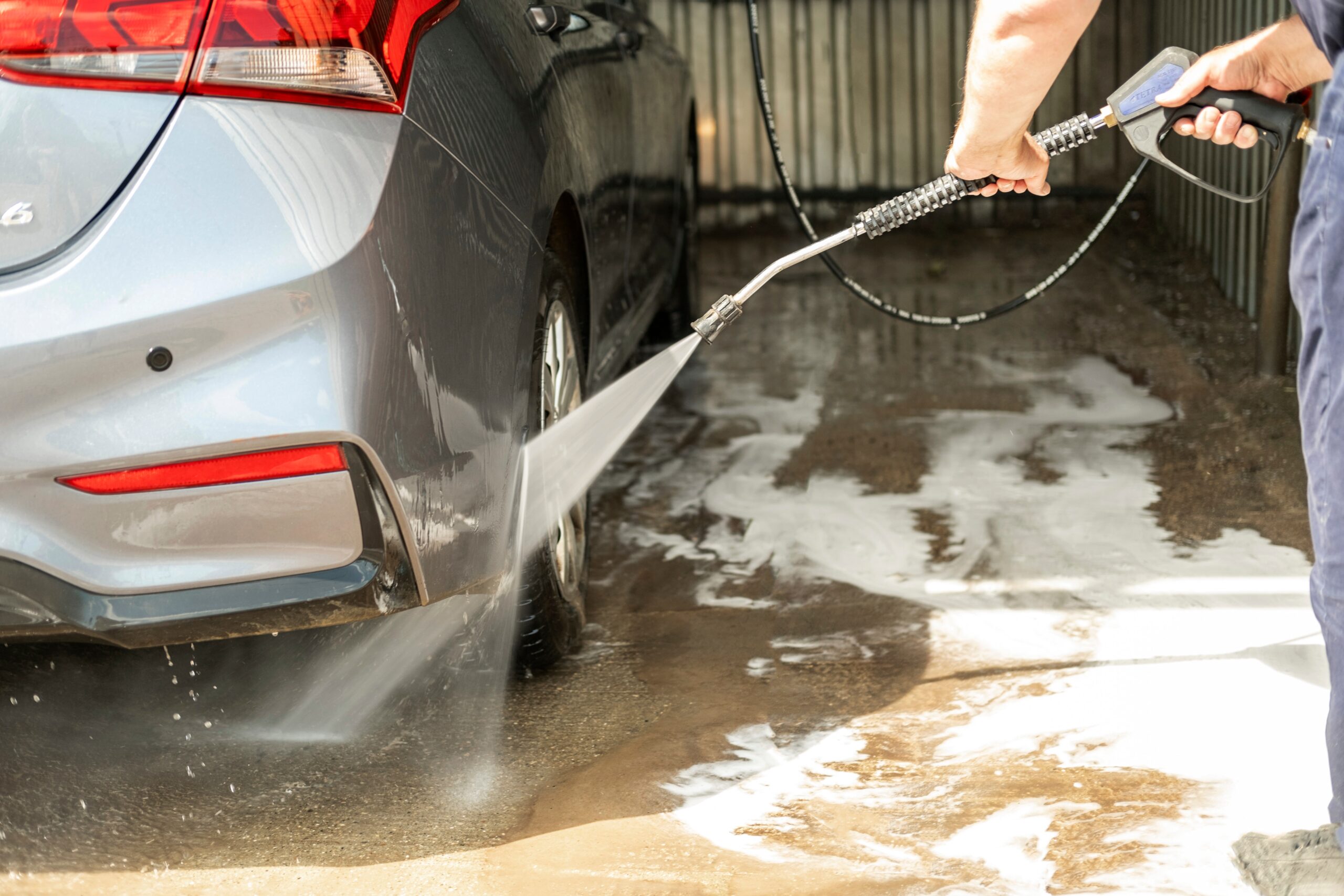 A car being rinsed off with a power washer